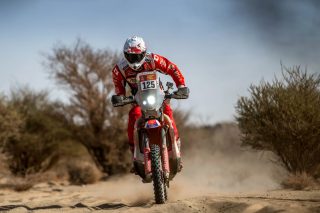 ゼッケン125番のホンダ製ダートバイクに乗り、砂漠のコースを走行するライダー