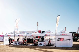 砂漠のような屋外で並ぶRSMOTO RACINGとHRC RACE SERVICEの白いテントとレーシングバイク