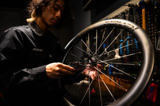 SPECIALIZEDのシャツを着たメカニックが、ROVALのカーボンホイールを丁寧に調整している様子。