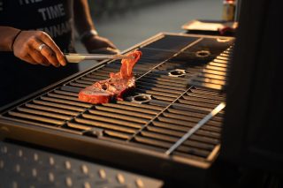 夕暮れ時、バーベキューグリルで肉を焼いている様子