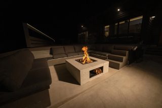 夜のモダンな屋外空間で、炎が燃えるファイヤーピット