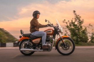 夕焼けを背景に走行中のオレンジ色のロイヤルエンフィールド メテオ350