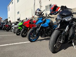 青い空の下、様々な色と種類のバイクが駐車場に整然と並ぶ