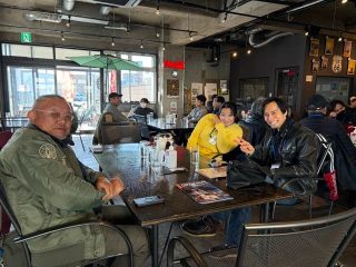 カフェのような場所で友人や知人らしき人々がテーブルを囲み、談笑