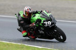 レーシングスーツ姿のライダーがKawasaki Ninjaでコーナリングする様子
