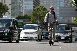 電動キックボードに乗って都市を走行する男性