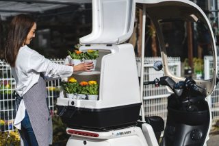 女性が花を積むEVデリバリー