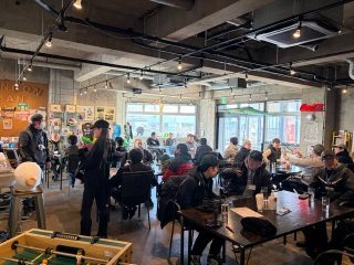 多くの人々がカフェのような広々とした空間に集まり、談笑