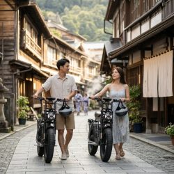 日本の伝統的な町並みを電動バイクを押して散策するカップル