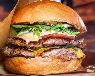 肉厚なパティが二枚挟まれ、とろけるチーズ、新鮮なレタスとトマト、そして特製ソースがたっぷりかかった、ボリューム満点のおいしそうなハンバーガー