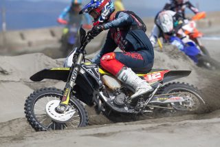 砂浜でレース中のオフロードバイクとライダー