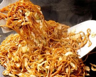 熱い鉄板の上で、香ばしい焼きそばが調理されている様子