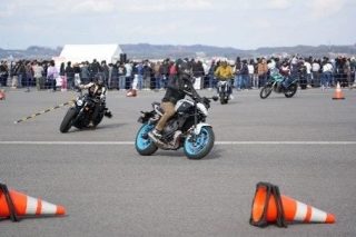 広々としたアスファルトの上で、複数のライダーがバイクに乗って走行しています