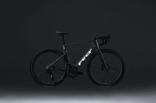 暗い背景に黒いロードバイクが中央に配置された写真