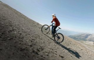 急勾配の砂利道を下るマウンテンバイカー