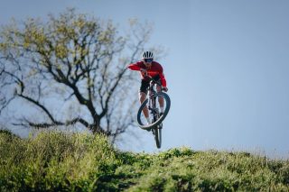 マウンテンバイカーが丘を飛び越えている画像