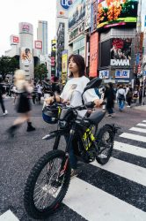 渋谷の街中で電動バイクに乗る女性