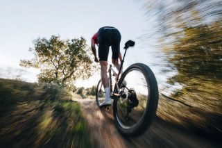 ダートコースを自転車で疾走する人物の後ろ姿