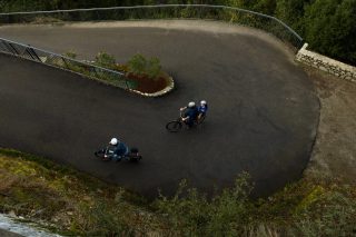 曲がりくねった舗装路を自転車で走る家族