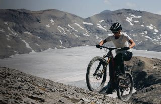 険しい山岳地帯をマウンテンバイクで登る人物