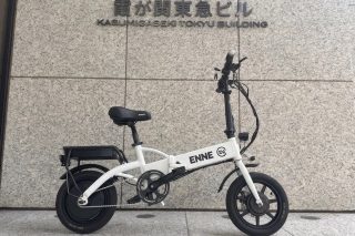 霞が関東急ビルの壁を背景に白い折りたたみ電動自転車