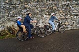 石垣沿いの道を自転車で走る家族