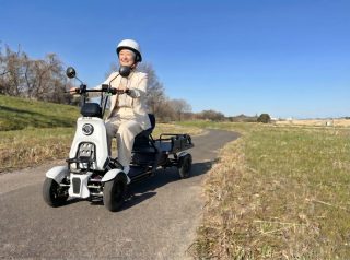 公園で白い電動カートを運転する高齢女性