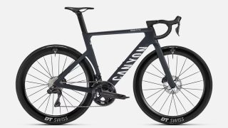 白い背景に置かれた、ダークグレーのCanyon Aeroad CF SLXロードバイクです。カーボンフレームにディスクブレーキ、DT Swissホイールを装備した高性能な競技用自転車が特徴的です。