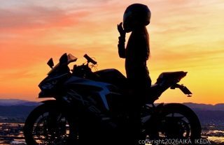 夕焼けを背景にバイクにまたがる女性