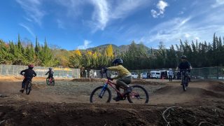 子供たちがヘルメットを着用し、土のコースで自転車に乗って楽しんでいる様子
