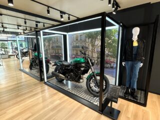 光の枠で展示された緑色のオートバイ