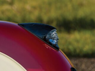 赤とクリーム色のオートバイのフェンダーに、インディアンヘッドのオーナメントが取り付けられているクローズアップ画像