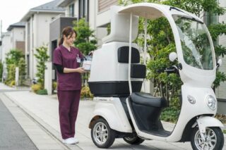 医療従事者が三輪電動スクーターに荷物を積んでいる様子