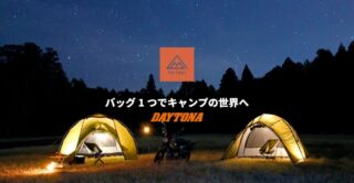 満点の星空の下、広々とした草原に2つのテントと1台のバイクが佇む夜のキャンプ風景です。中央には「DAYTONA」のロゴと「バッグ1つでキャンプの世界へ」というメッセージがあり、アウトドアブランドのプロモーションを思わせます。