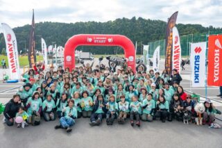 多くの女性ライダーたちがバイクイベントで集合写真を撮っている様子