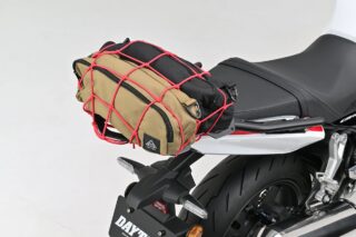 バイクのリアシートに、ベージュと黒のバッグが赤いカーゴネットでしっかりと固定されている