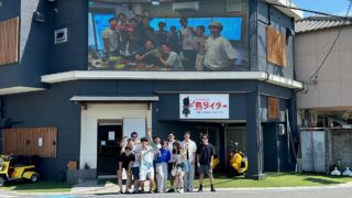 島ライダーの店舗前で集合写真を撮る若者たち