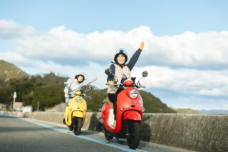 スクーターに乗って手を振る二人組の女性